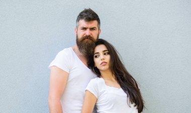 Kaç arkadaş birlikte takılmak. Gençlik şık kıyafet basit ama modern. Genç ve şık. Çift beyaz gömlek gri duvara yakın kucaklamak. Acımasız ve şık moda kız takılmak hipster sakallı
