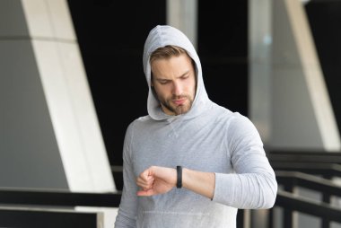 Biraz ara. Adam atlet zaman akıllı izle kentsel arka plan kontrol yüz konsantre. Atlet kıl ile akıllı saate benziyor. Sporcu pedometre gadget ile eğitim. Akıllı izle gadget concept