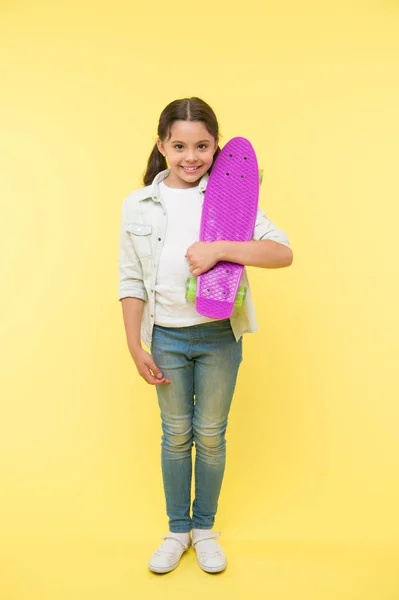 Klaar om te rijden. Kind meisje gelukkig draagt penny board. Kind houdt van skateboarden met penny board. Moderne tienerhobby. Hoe je skateboard moet rijden. meisje gelukkig gezicht draagt penny board geel achtergrond — Stockfoto