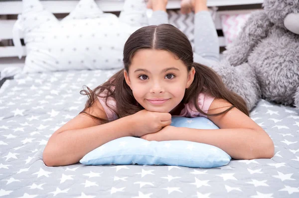 Relajándome. Niña acostada sobre una almohada en su dormitorio. El chico se prepara para ir a la cama. Agradable tiempo elegante interior. Niña de pelo largo lindo pijama relajante en la almohada en el dormitorio. Hora de dormir o dormir la siesta — Foto de Stock