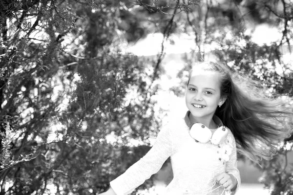 Ragazzo ballerino sorridente con lunghi capelli volanti. Happy girl balla con la musica nel parco estivo. Bambino piccolo godere di musica in cuffie all'aperto. Suono melodico e mp3. Divertimento estivo e gioia — Foto Stock