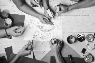 Sanatçı ahşap masa boyalar ve renkli kağıt ile. İşaretleri erkek ve kadın elinde beyaz kağıt üzerine çizmek