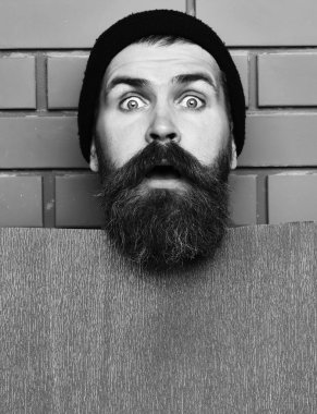 kahverengi tuğla duvar studio arka plan, kopya alanı üzerinde kağıt levha. Sakallı acımasız beyaz hipster kırmızı kağıt levha ile