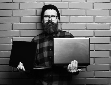 dizüstü bilgisayarlar kırmızı siyah damalı gömlek şapka ve gözlük kahverengi tuğla duvar studio arka planda, sakallı acımasız beyaz hipster dizüstü bilgisayarlar holding holding hipster