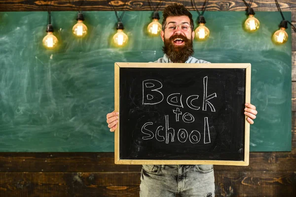 Lise kavramı. Adam sakal ve bıyık neşeli gülümseyen yüz memnuniyetle öğrencilerin, kara tahta arka plan ile. Gözlük öğretmen okul için başlıklı yazı tahtası tutar