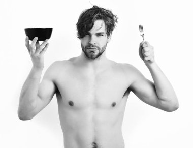 beyaz stüdyo arka plan üzerinde izole çatal ile siyah kase tutarak. Beyaz seksi genç maço siyah kase çatalla holding