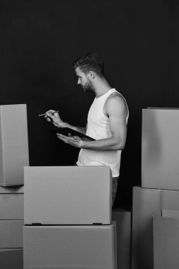 Teslimat ve kavram olarak hareket. Adam siyah arka plan üzerine karton kutular sayma