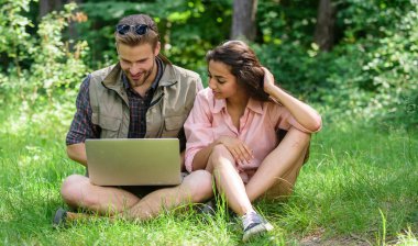 Çift gençlik eğlence dizüstü bilgisayar ile açık havada harcamak. Modern teknolojileri online ve herhangi bir çevre koşulları çalışmalarına olmak için fırsat verir. Adam ve kız dizüstü bilgisayar ekranına bakarak. Doğaya daha yakın.