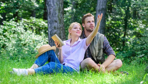 Romantic couple students enjoy leisure looking upwards observing nature background. Romantic date at green meadow. Couple in love spend leisure in park or forest. Couple soulmates at romantic date