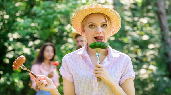 Альтернативное питание для вегетарианцев. Она предпочитает овощи. Вегетарианский образ жизни её выбор. Выбор мяса или овощей. Вегетарианцы питательный выбор. Девушка держит вилки с колбасой и огурцом
