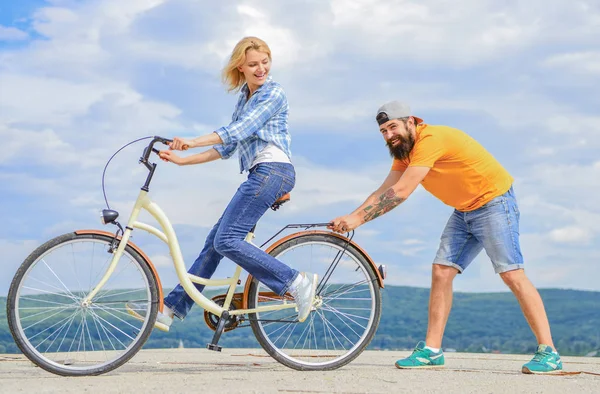 Διδάξτε ενήλικα σε ποδήλατο. Άνδρας βοηθά στη διατήρηση ισορροπίας και το ποδήλατο. Για να βρείτε ισορροπία. Γυναίκα βόλτες με ποδήλατο φόντο του ουρανού. Πώς να μάθουν να οδηγούν ποδήλατο ως ενήλικας. Ποδηλασία, ενώ ο φίλος κορίτσι υποστήριξη της — Φωτογραφία Αρχείου