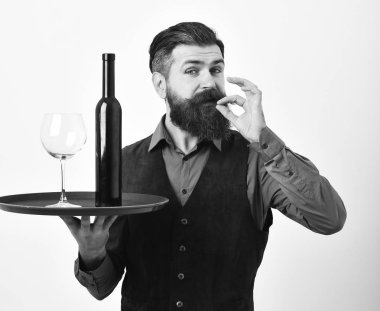 Barmen kırmızı şarap mükemmel tat işaret gösteren hizmet vermektedir. Garson ile cam ve şişe şarap tepsi.