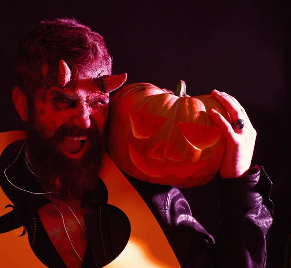 Monstruo celebra el festival de octubre. Concepto fiesta de Halloween. Hombre con el maquillaje de miedo sostiene corte silueta de calabaza en el cuello — Foto de Stock