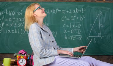 Resmi olmayan bir ortamda ders. Kadın öğretmen dizüstü sit tablo sınıf kara tahta arka plan tutun. Modern nesil öğretmeni. İnanılmaz öğretim görevlisi bayanı tanıyor nasıl dokunmatik modern nesil kal