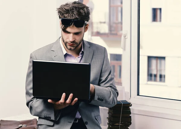 Working online and gadgets concept. Man or manager with bristle and serious face in sunglasses