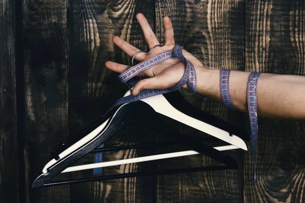 Αρσενική χέρι εκμετάλλευση κρεμάστρα σε φόντο ξύλινη — Φωτογραφία Αρχείου