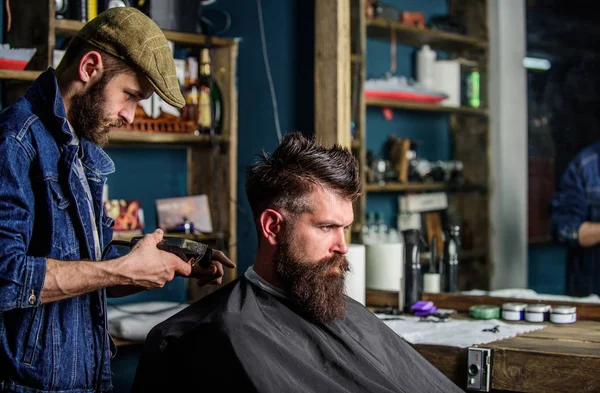 Barbeiro com clipper aparar o cabelo na nuca do cliente. Um cliente Hipster a cortar o cabelo. Barbeiro com cortador de cabelo funciona no corte de cabelo do barbeiro barbudo fundo. Conceito de estilo de vida Hipster — Fotografia de Stock