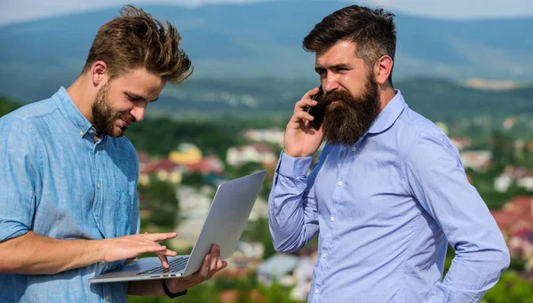 Business partners in formal wear with laptop and phone taking advantages of mobile internet working outdoor. Mobile internet concept. Colleagues with laptop work outdoor sunny day nature background