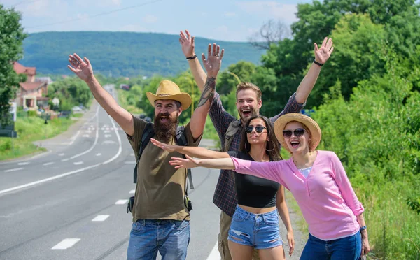 Los viajeros tratan de detener el coche. Amigos autoestopistas viajando verano día soleado. Compañia amigos viajeros autoestop en borde camino naturaleza fondo. Comience una gran aventura en su vida con autoestop —  Fotos de Stock