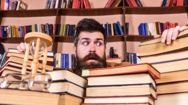 Öğretmen ya da öğrenci sakallı defocused kitaplar ile masada oturur. Adam korkmuş yüz Kitaplığı'nda, eğitim sırasında kitaplar, kitap rafı arka plan üzerinde yığınları arasında. Kazık kavramı