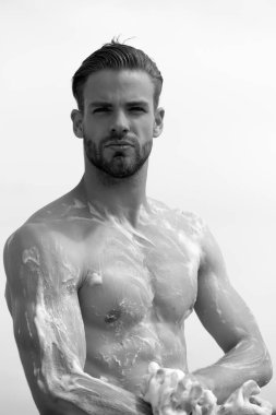 Adam kıl ve beyaz arka plan üzerinde ciddi bir yüz. Sünger ile çıplak göğüs Yıkama maço. Adam köpükle kaplı