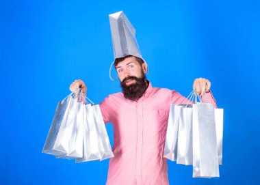 Kafasında torba ile gülümseyen yüzünde hipster bağımlısı Alışverişkoliğin var. Alışveriş kavramı. Satış sezon indirimlerle alışveriş adam. Sakal ve bıyık taşır alışveriş torbaları, mavi arka plan ile adam