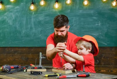 Çocuk, Çocuk koruyucu kask babamla tornavida kullanmayı öğrenme içinde meşgul. Atölye kavramı çalışmasında. Baba, sakallı aracı tornavida kullanmak için küçük oğlu öğretim üst