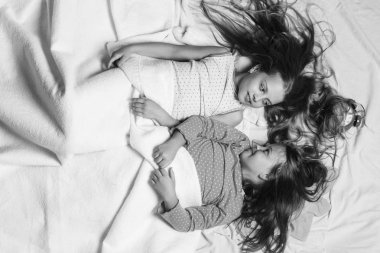 Çocuklarla bağsız kıl pembe bir arka plan üzerinde ve baktılar yüzler. Pembe pijama çocuklarda beyaz battaniye ile örtülü.