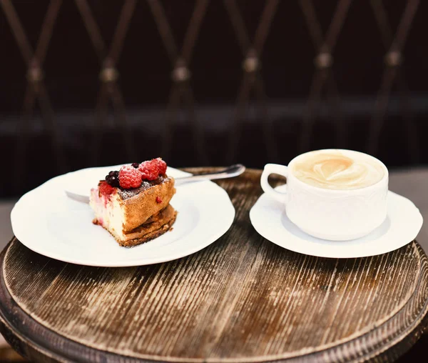 Patisserie concept. Cheesecake with berries and coffee on wooden table — Stock Photo, Image