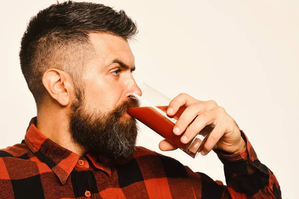 Guy shows his harvest. Man with beard drinks tomato juice isolated on white background