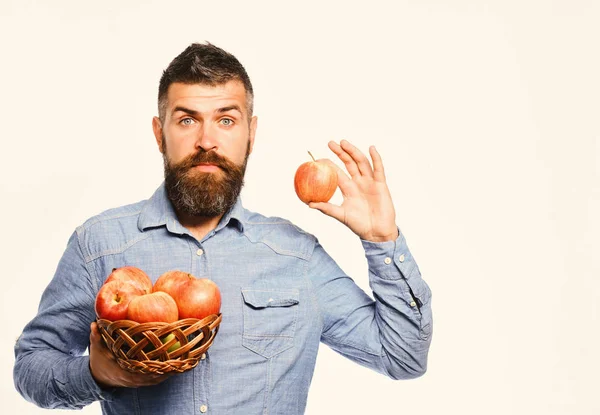 수염을 가진 남자 고 애플 과일 흰색 배경에 고립 된 고리 버들 세공 그릇. 놀란 얼굴로 농부 보유 빨간 사과 — 스톡 사진