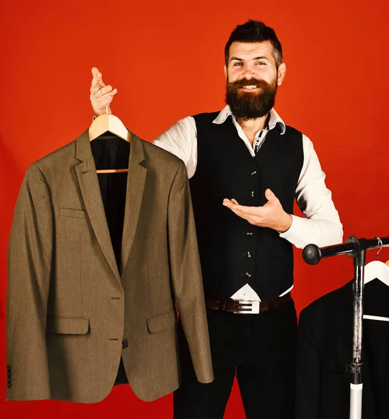 Designer and suit on clothes hanger. Man with beard by clothes rack. Fashion and individual style