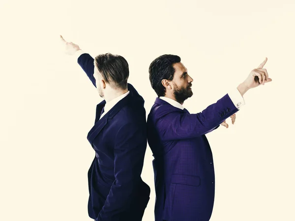 Les jeunes hommes d'affaires pointant dans deux directions différentes en même temps — Photo