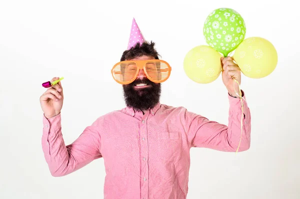 Parteikonzept. Hipster mit Riesensonnenbrille feiern Geburtstag. Mann mit Bart und Schnurrbart auf glücklichem Gesicht hält Luftballons, weißer Hintergrund. Mann im Partyhut mit Partyhorn feiert — Stockfoto