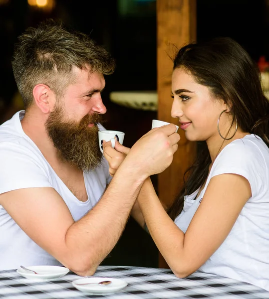 Couple in love drink black espresso coffee in cafe. Man with beard and attractive happy smiling girl drinking coffee. Couple happy spend time in cafe. Share romantic feelings with cup of coffee