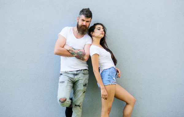 Youth stylish outfit simple but modern. Couple friends hang out together. Young and stylish. Couple white shirts cuddle near grey wall. Hipster bearded brutal and stylish fashionable girl hang out