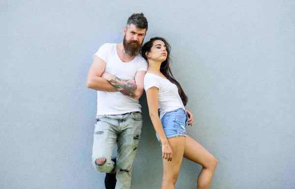 Jeugd stijlvolle outfit eenvoudig maar modern. Paar vrienden hangen samen. Jong en stijlvol. Paar witte shirts knuffelen in de buurt van grijze muur. Hipster bebaarde brutale en stijlvolle modieus meisje hangen — Stockfoto