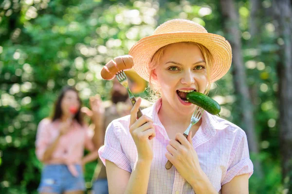 Girl smiling face holds forks with sausage and cucumber. Vegetarian lifestyle is her choice. Alternative nutrition for vegetarians. Vegetarians nutritional choice. Choice between meat or vegetables — Stock Photo, Image