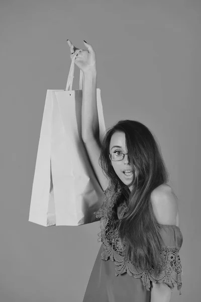 Beauty and fashion concept. Lady stands on yellow background holding pink shopping bag up. — Stock Photo, Image