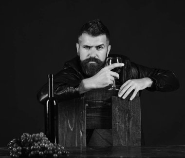 Sakallı adam şarap koyu kahverengi zemin üzerinde tutar. Sommelier tahta sandalyede eğilir. Şarapdenemeye ve degüstasyon kavramı.