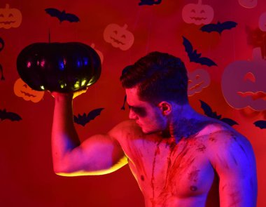 Yüzünde ve göğsünde kan olan adam kaslarını gösteriyor..