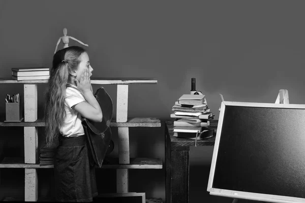 De volta ao conceito de escola e infância. A rapariga está perto do quadro negro, a copiar espaço. Material escolar e infantil — Fotografia de Stock