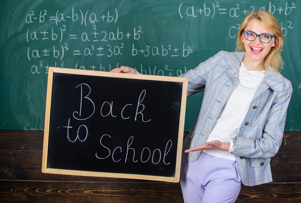 Le professeur accueille la nouvelle année scolaire. Dame éducatrice en classe se préparer pour la nouvelle année scolaire. Début de la nouvelle saison scolaire. Femme professeur costume formel détient inscription tableau noir retour à l'école — Photo