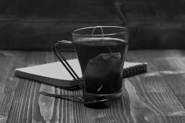 Herbstabendkonzept. Tee und Notizbuch auf Holzgrund. Glas schwarzen Tee — Stockfoto