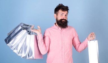 Hipster gülümseyen yüzü üzerinde alışveriş torbaları taşır. Satış ve indirim kavramı. Satış sezon indirimlerle alışveriş adam. Tezgâhtar, açık mavi renkli olarak sakal ve bıyık işler ile adam