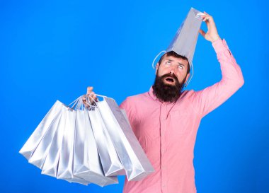 Satış sezon indirimlerle alışveriş adam. Alışveriş kavramı. Yüz kafasına torba ile acı üzerinde hipster bağımlısı Alışverişkoliğin var. Sakal ve bıyık taşır alışveriş torbaları, mavi arka plan ile adam