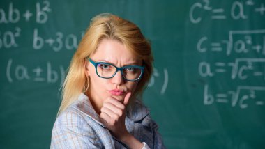 Matematik görev çözmek. Bu görevi çözmek. Okul eğitim temel bilgi. Bayan gözlük akıllı öğretmen sınıf kara tahta arka plan giymek, yakın çekim. Öğretmen kadın çözme hakkında düşünüyorum ve neden