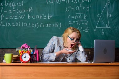 Çok gerçek okul gün çalışıyorum. Öğretmen evrak ve araştırma ile meşgul. Öğretmen sınıfları sonra çalışmaya yüz devam yorgun. Hâlâ çalışıyor. Öğretmen kadın sit tablo sınıf kara tahta arka plan