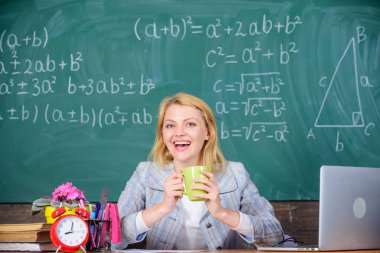 Çok iyi sonra sınıflar rahatla. Aday öğretmenler göz önünde bulundurmanız gereken çalışma koşulları. Öğretmenler için çalışma koşulları. Gülümseyen kadın öğretmen kupa içki sınıf kara tahta arka plan tutar