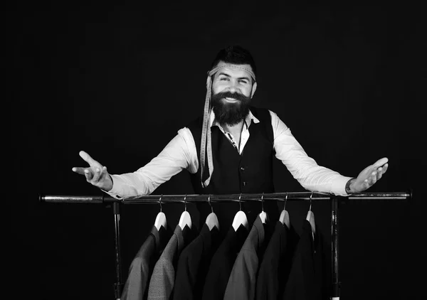 Diseñador se apoya en perchas de ropa. Hombre con barba por perchero. Concepto de sastrería y diseño — Foto de Stock